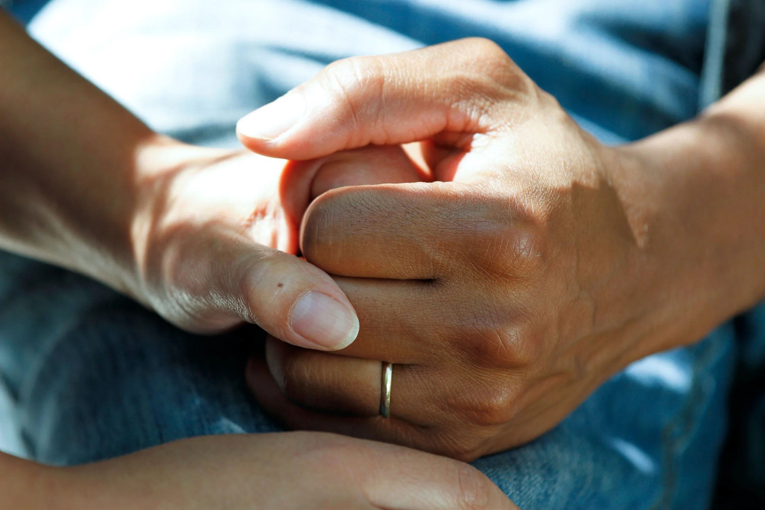 Couples hold hand after birth trauma therapy that they are working with online counseling in florida with April Brown, LMFT, who is a miami marriage therapist.